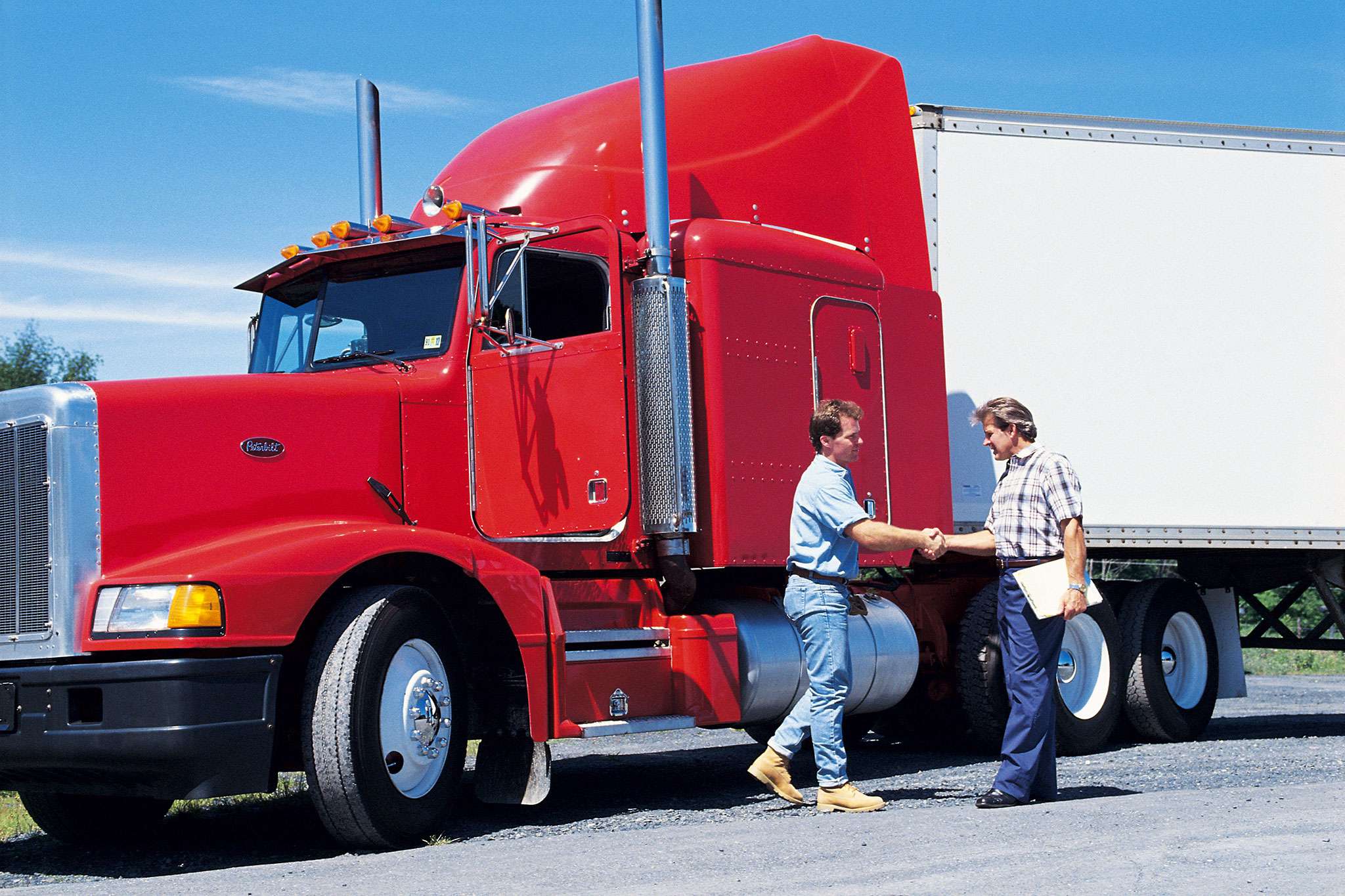 two workers shaking hands in front of a semi truck